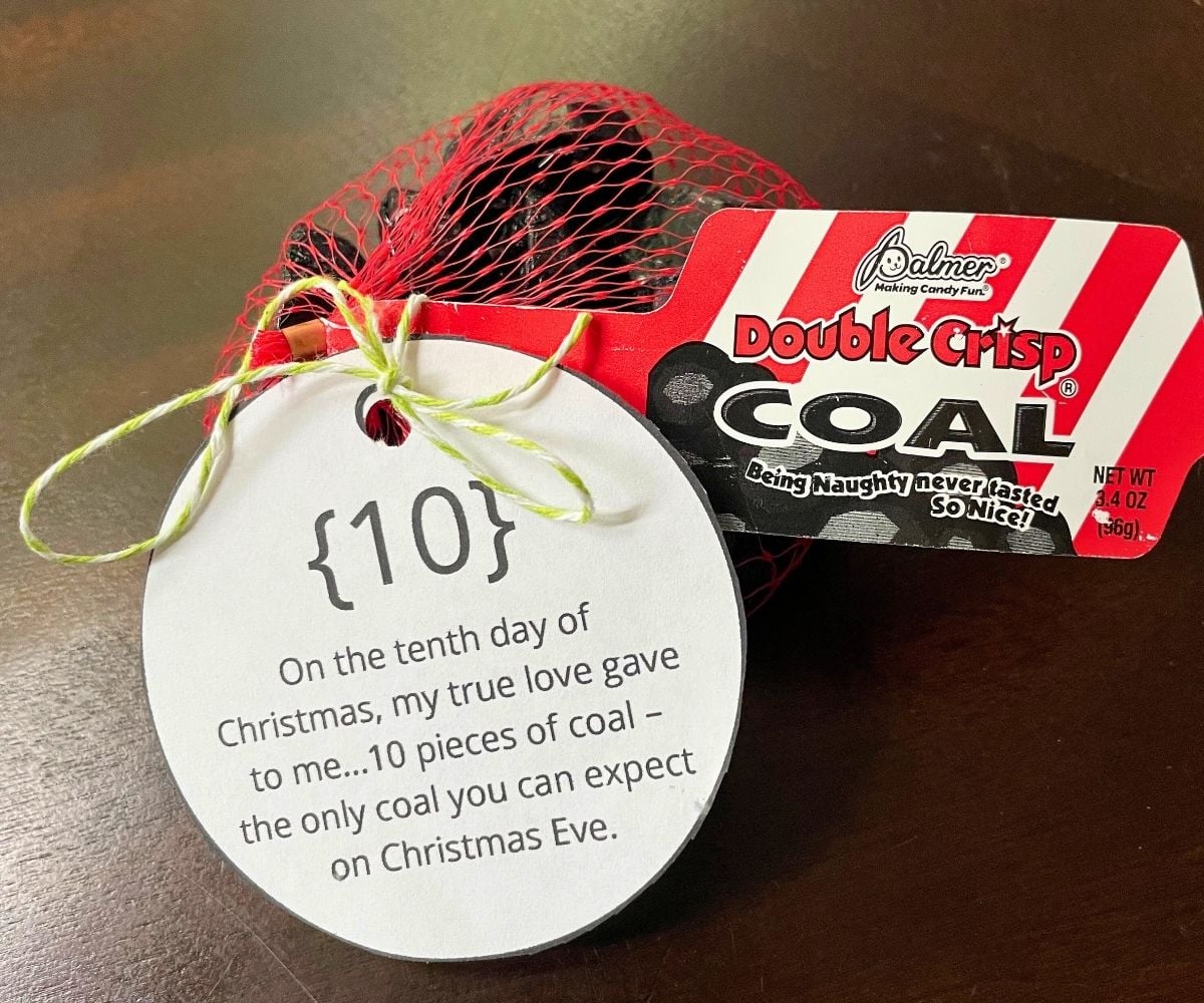 red bag of chocolate coal candies with ornament shaped tag on it