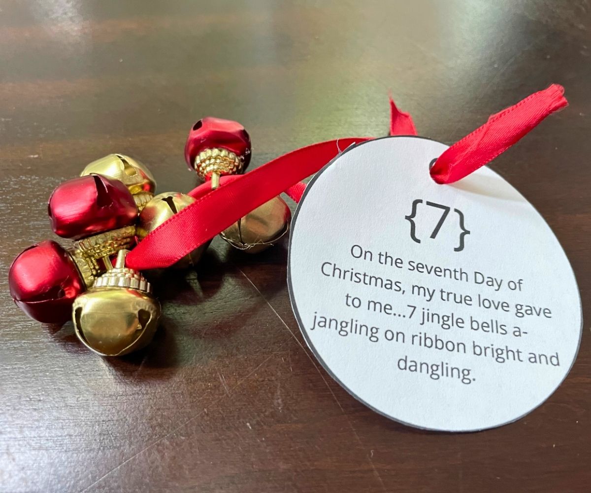 red ribbon with 7 jingle bells on it, with ornament shaped tag tied to it