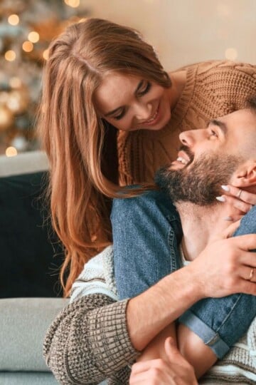 couple cozying up together on couch with tree in background