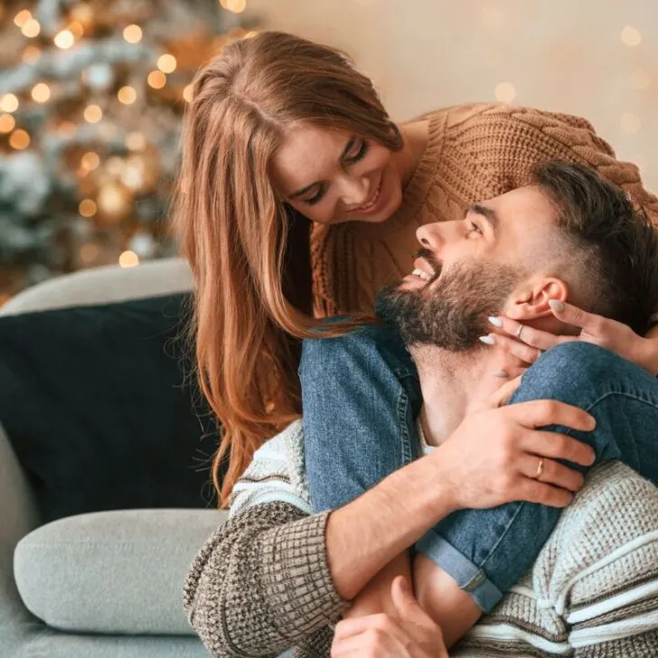 couple cozying up together on couch with tree in background