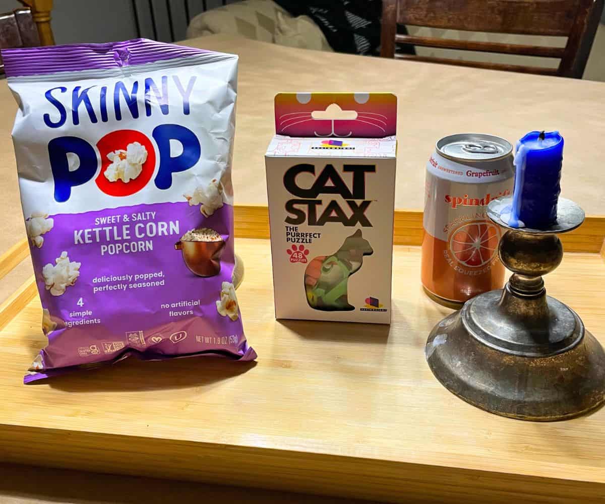 wooden tray with cat stax, can of spindrift, skinny pop, and a candle