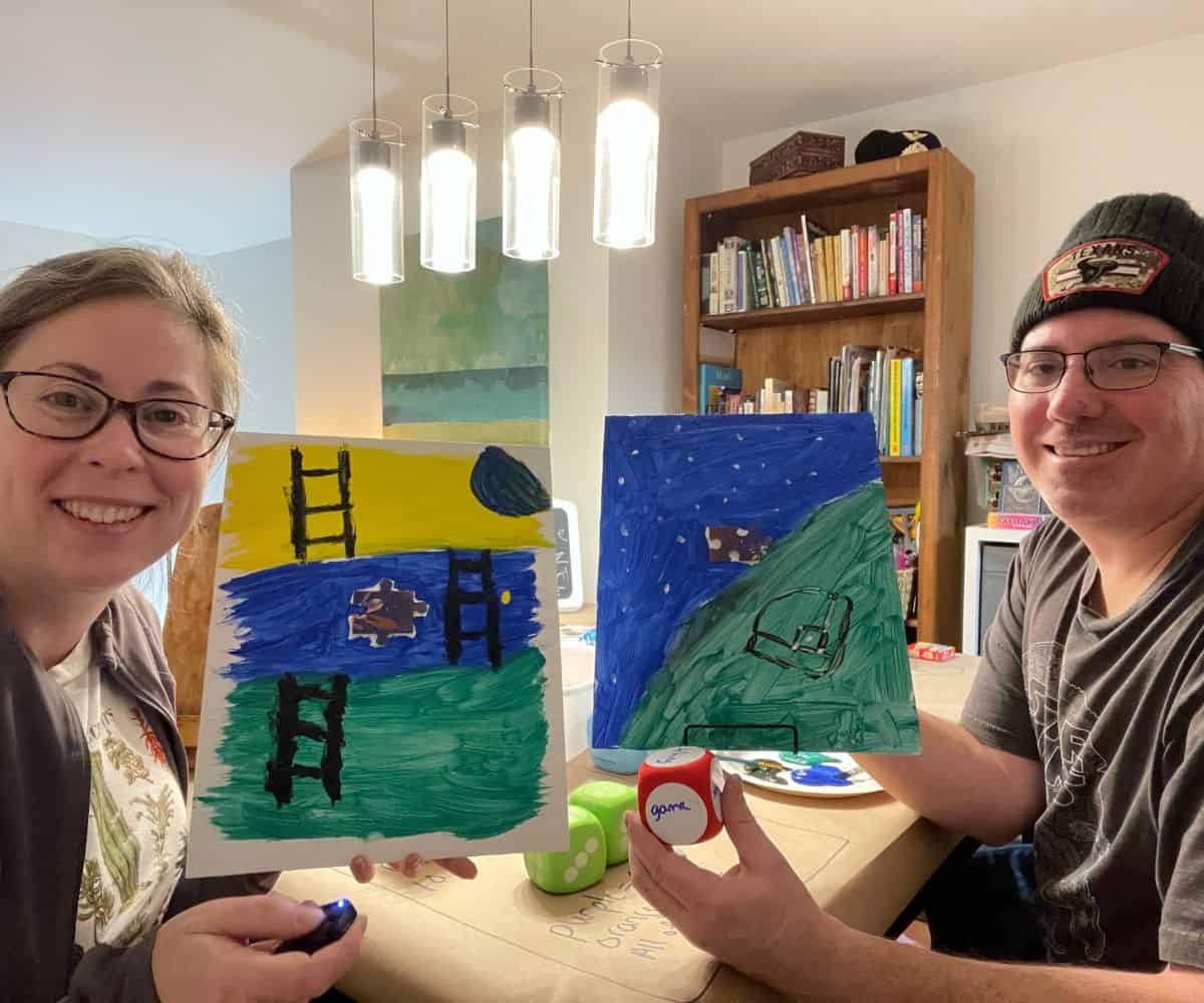 husband and wife holding up their puzzle piece paintings, finished, and smiling