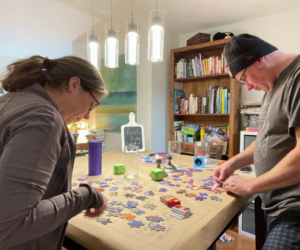 couple with Uno deck, working on putting puzzle pieces together and competing