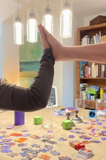 couple high fiving each other with tons of puzzle pieces on table