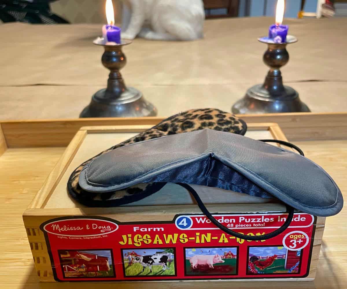 wooden box of kids puzzles with two blindfolds, and two candles lit in background