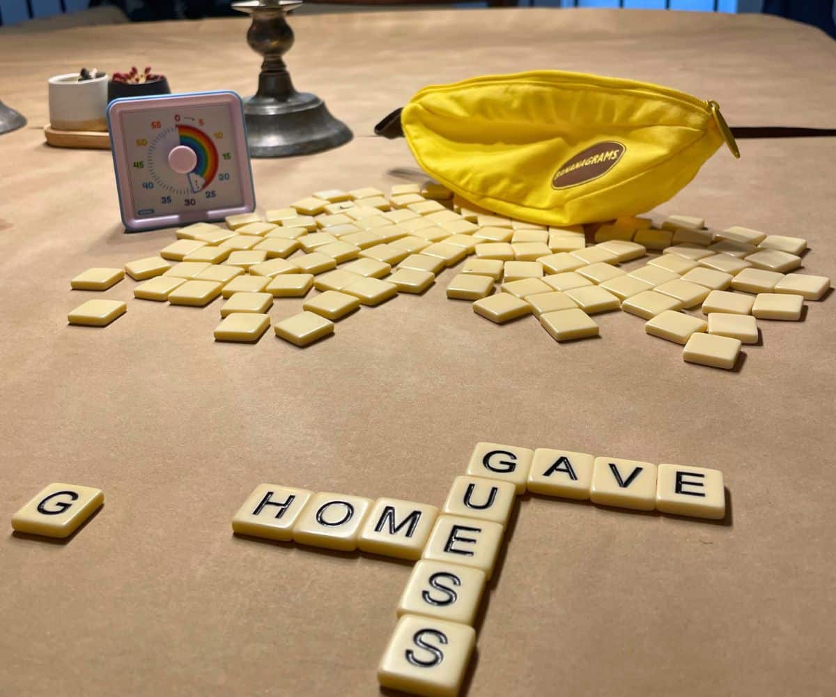 bright yellow bananagrams bag, all the tiles on table with a rainbow countdown timer