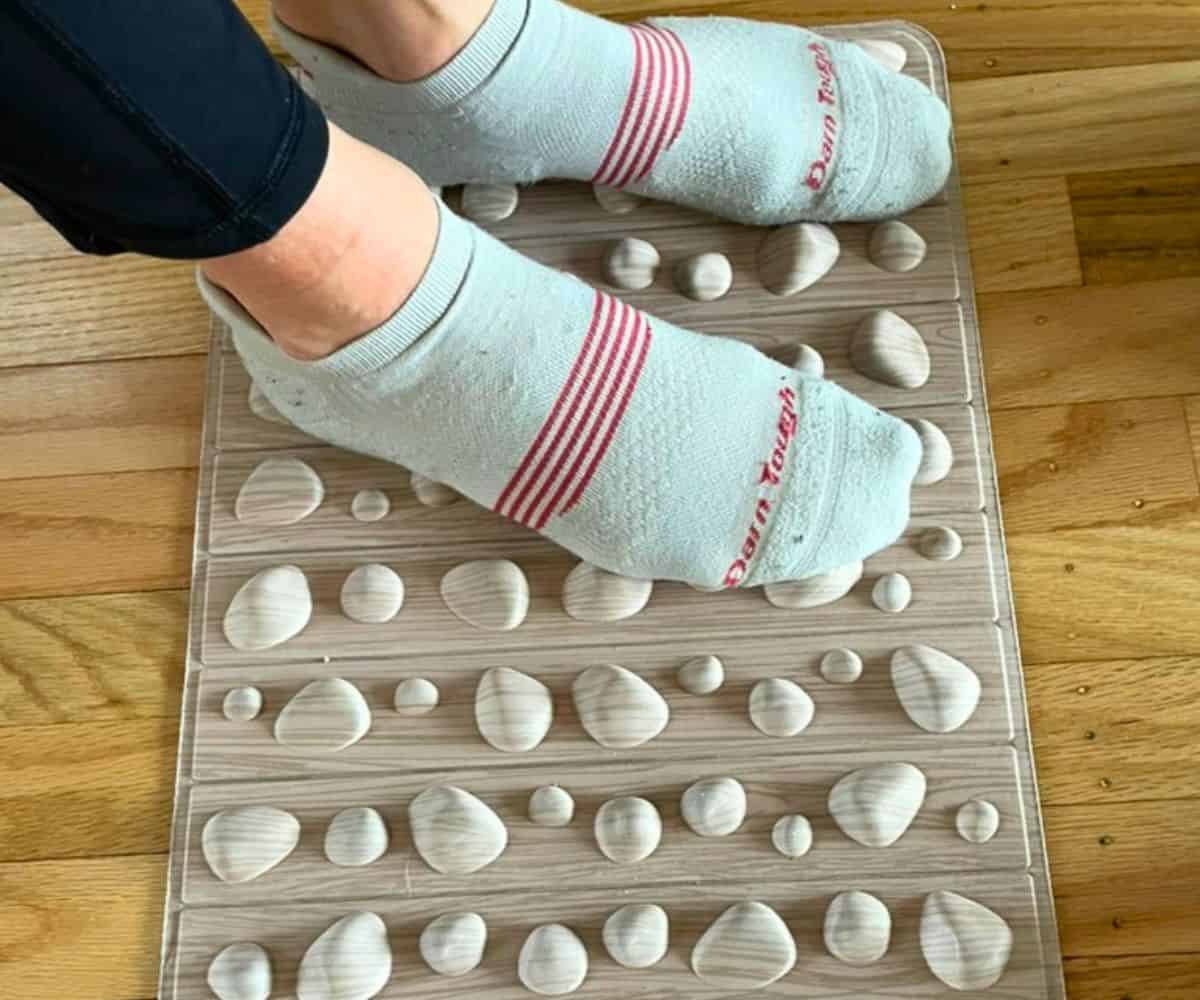 woman's feet in socks on pebbled accupressure mat