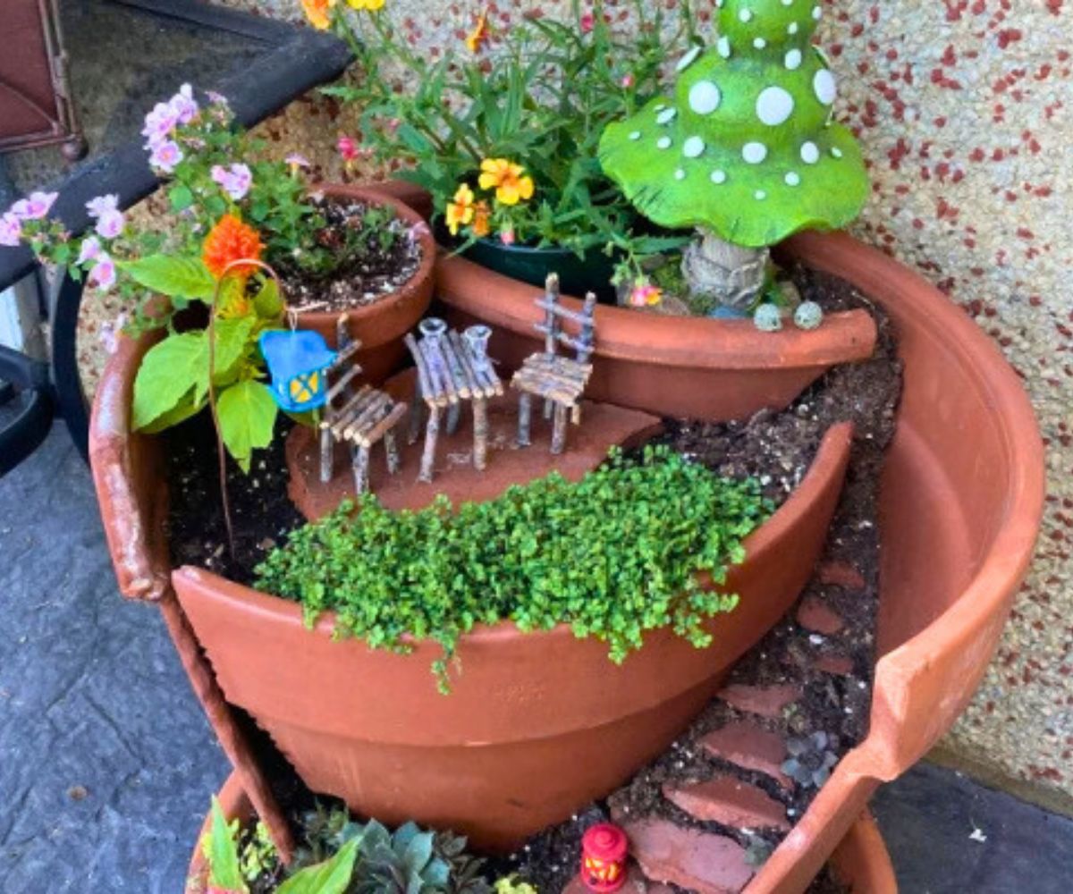 ornate fairy garden with spiral staircase made out of broken clay pots