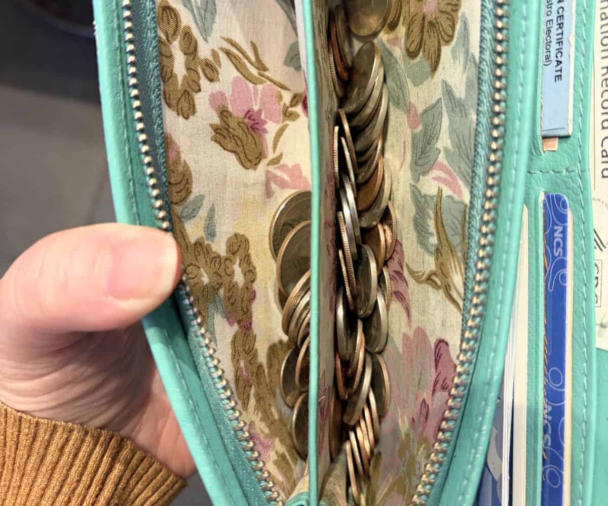 author opening up the change portion of her teal colored wallet