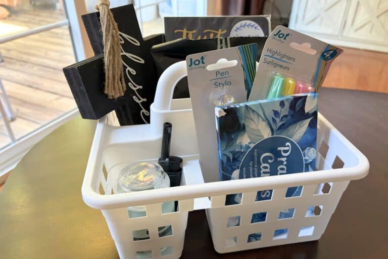 Bible studying supplies in a white shower caddy on dark table