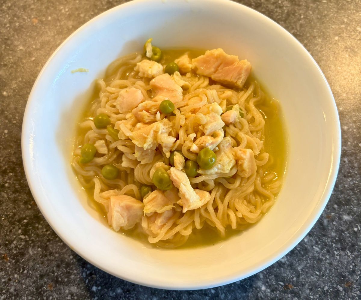 white bowl of ramen soup with noodles, chicken, and peas