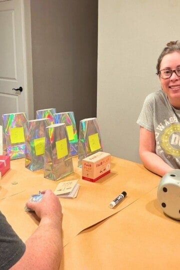 author and husband smiling at camera and about to roll dice to choose chore schedule for adults