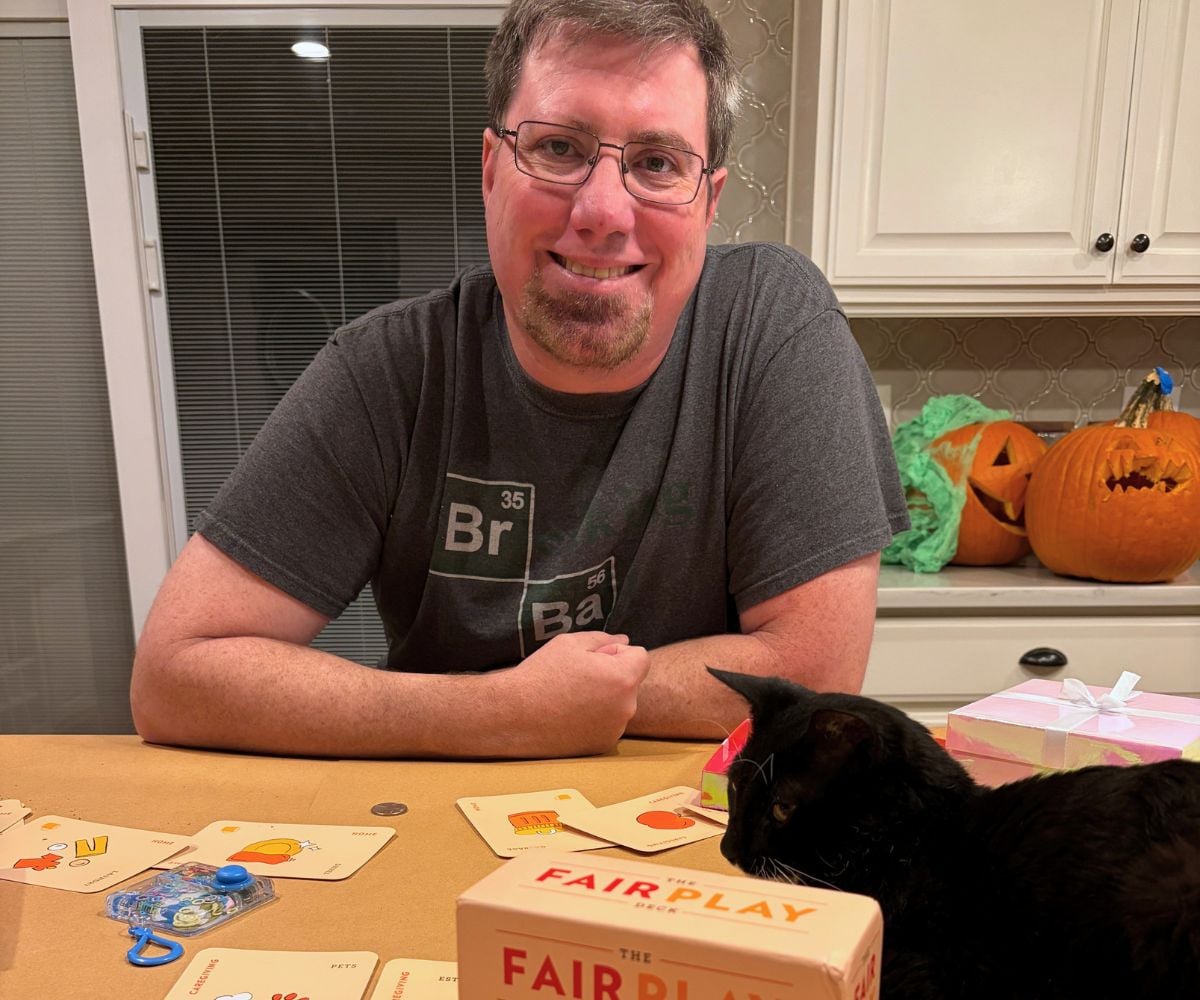 husband smiling with lots of cards all over the table